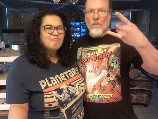 Photo of my wife and I making silly faces, both of us wearing Ogdimora cat-themed t-shirts.