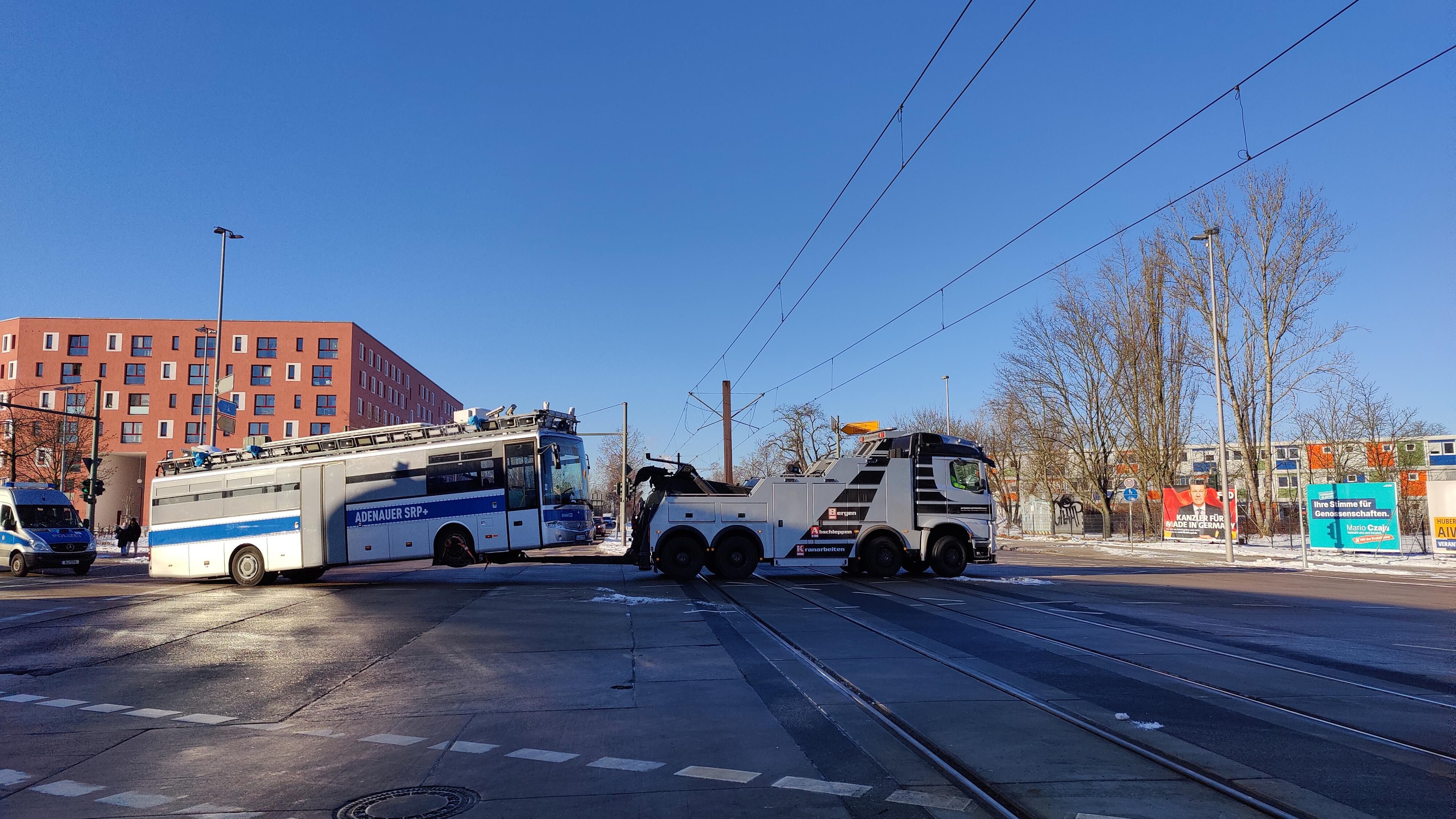 Der Adenauer SRP+ wird von einem großen Abschleppfahrzeug die Kreuzung Blumberger Damm und Landsberger Allee um die Kurve Richtung Westen geschleppt. Hinter dem Adenauer SRP+ ist noch ein weiterer Polizeibus.