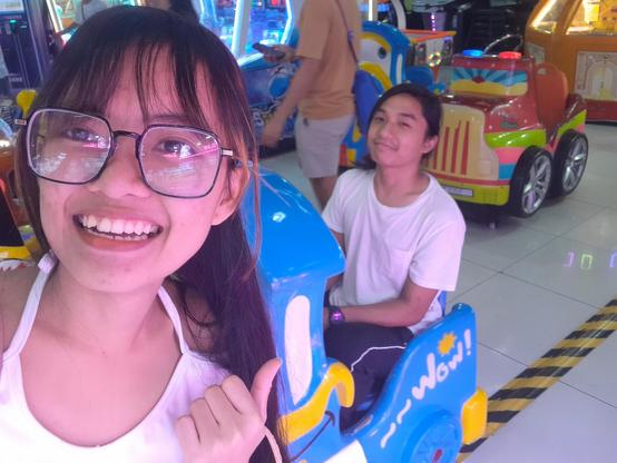 girl with glasses taking a selfie with a guy on a kiddie ride from an arcade