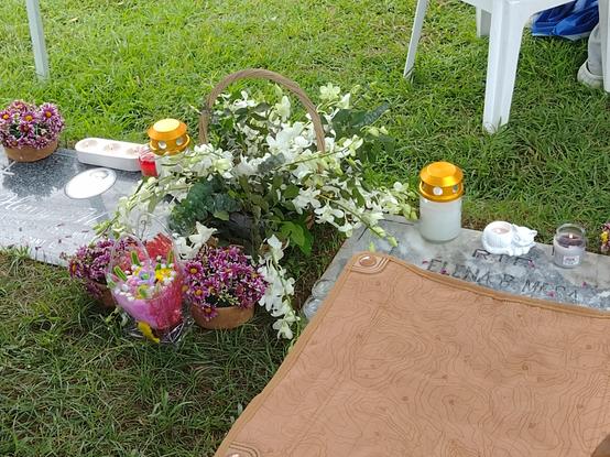 A couple of graves decorated with an assortment of flowers and candles
