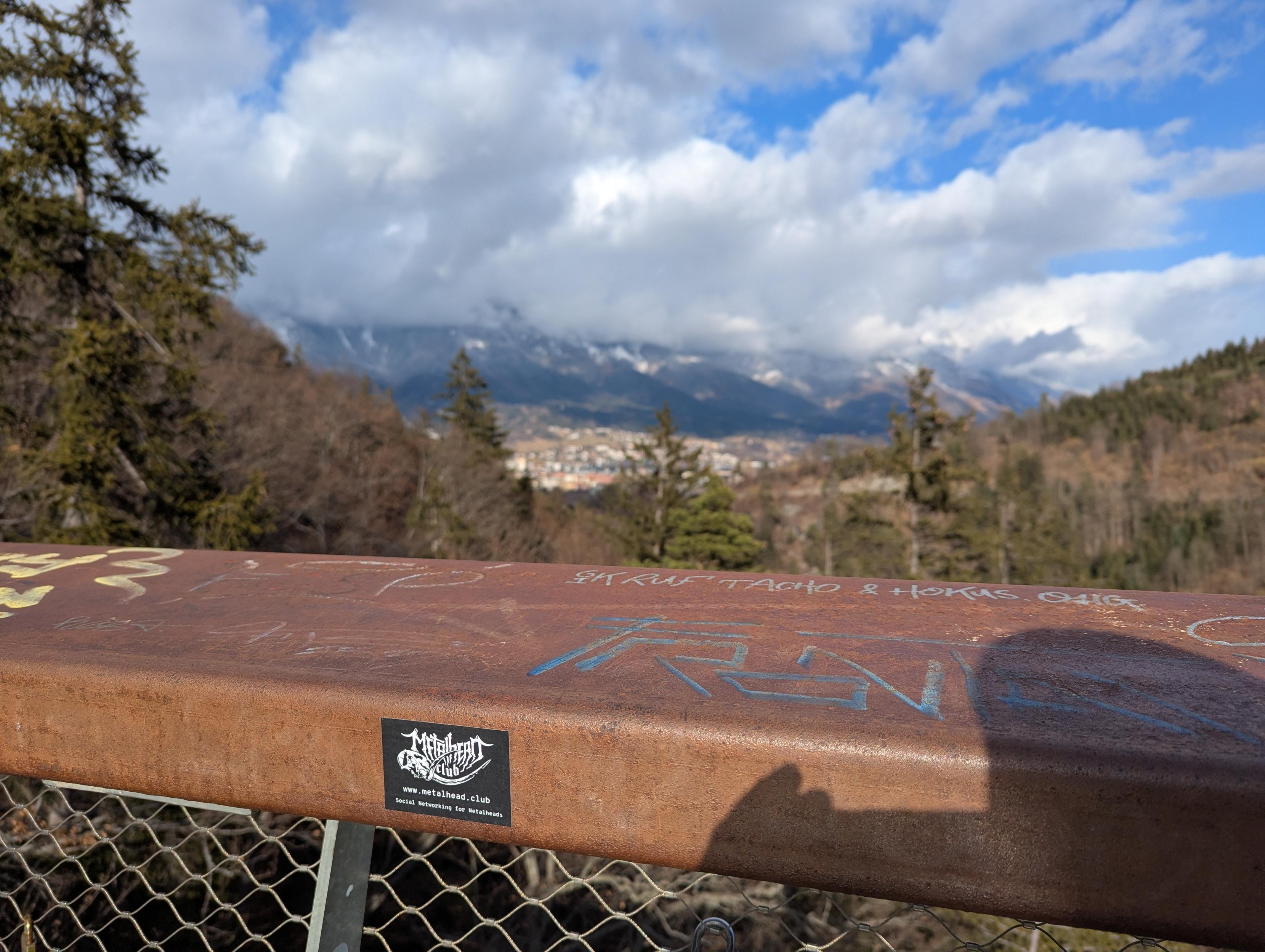 Metalhead.club Sticker auf Aussichtsplattform. Dahinter Wald.