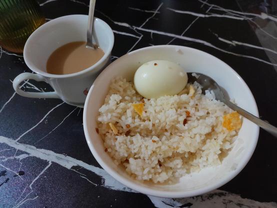 Bowl of steamed rice (mixed with chili garlic and potato chips) with boiled egg, and a cup of coffee