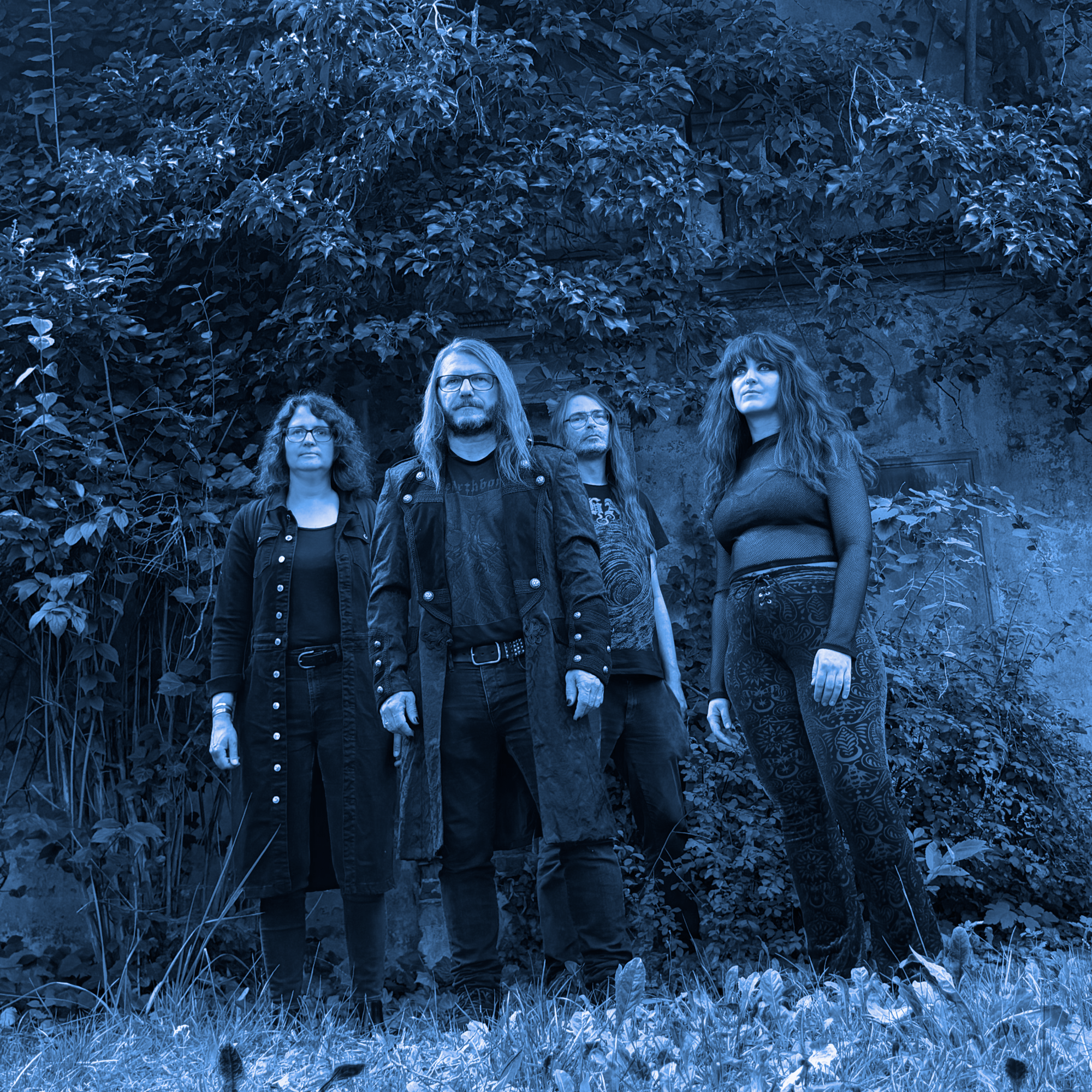 A blue-tinted band photo of Stoned Medusa at the cemetery. On the left is the drummer, in the middle left is the guitarist, in the middle right is the bassist, and on the right is the singer.